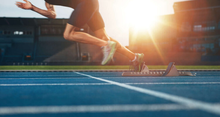 Athlete runner feet running on treadmill closeup on shoe - Track and field runner in sport uniform at starting position - Fitness lifestyle, sport and healthy concept